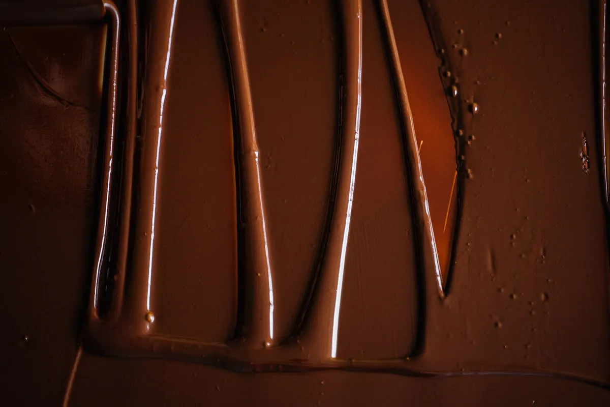 Chocolate atemperado fluido extendido sobre una mesa en pliegues brillantes