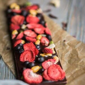 Artistic chocolate bar topped with dried berries and nuts on parchment paper.